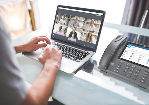 A modern office desk with a business phone and laptop